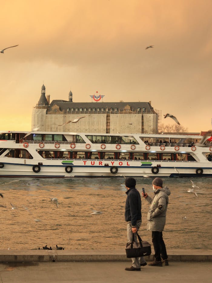 gallery-5 Men watching seagulls next to Turyol ferry on the Bosphorus in Istanbul with a warm sunset glow.