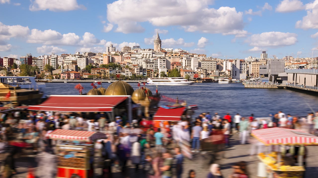 Blurred pedestrians on a lively promenade in Istanbul with Galata Tower and skyline in view.