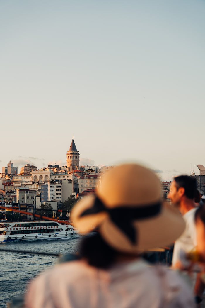 Charming view of Galata Tower and Istanbul skyline at sunset with people on waterfront.